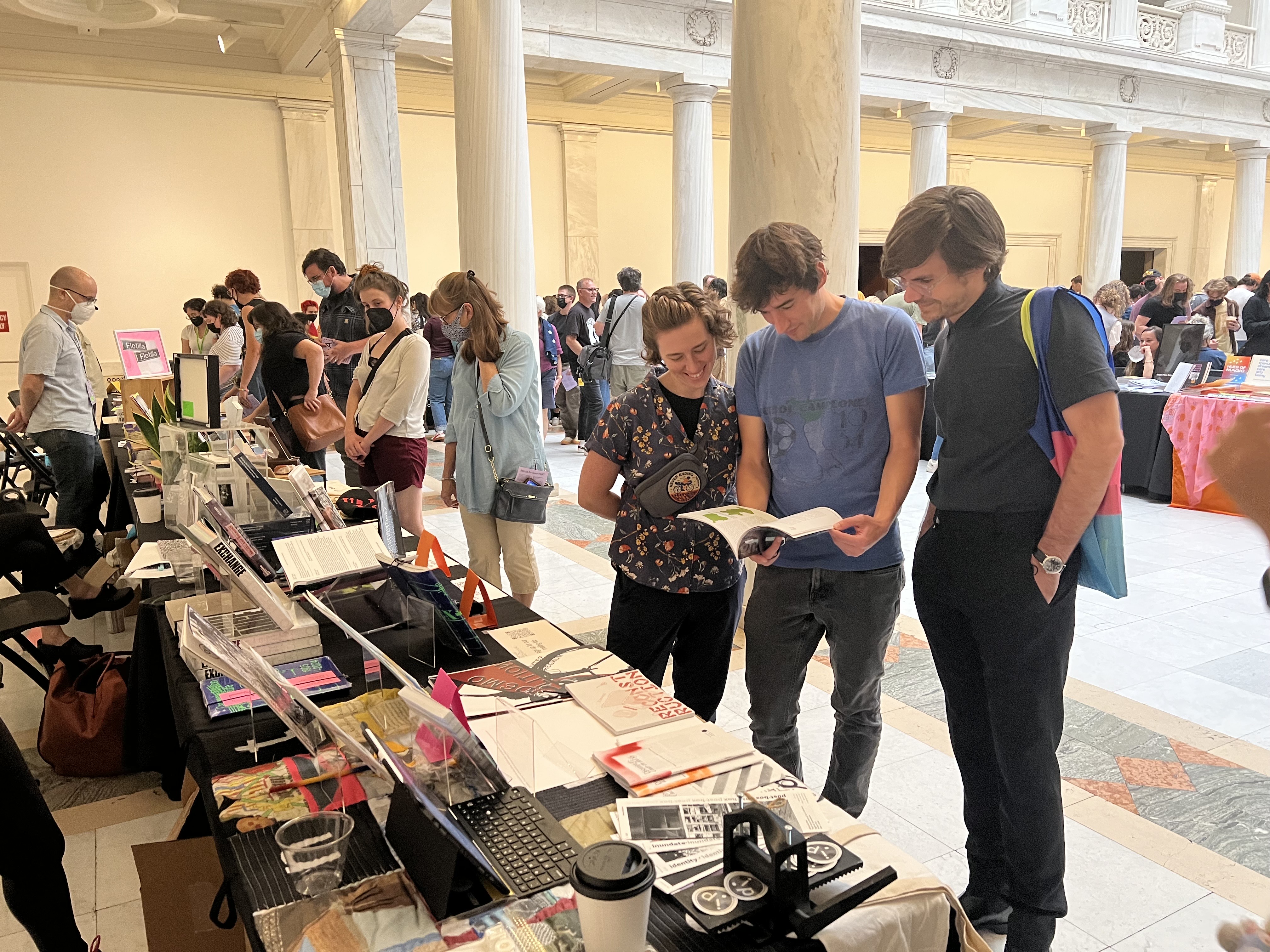 Visitors at the Carnegie Mellon Architecture table at the Pittsburgh Art Book Fair peruse a book.