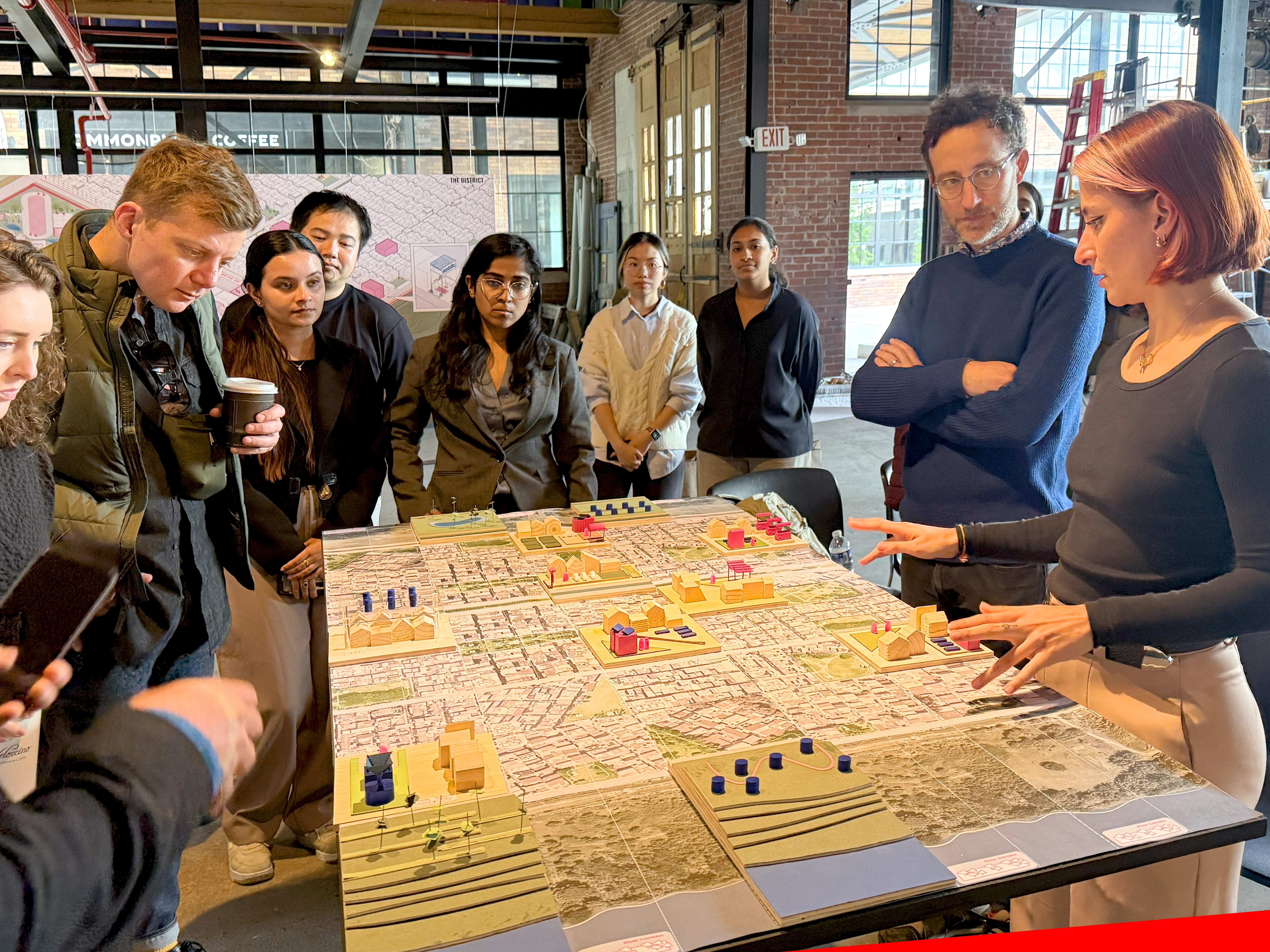 MUD students and faculty gather around a thesis project