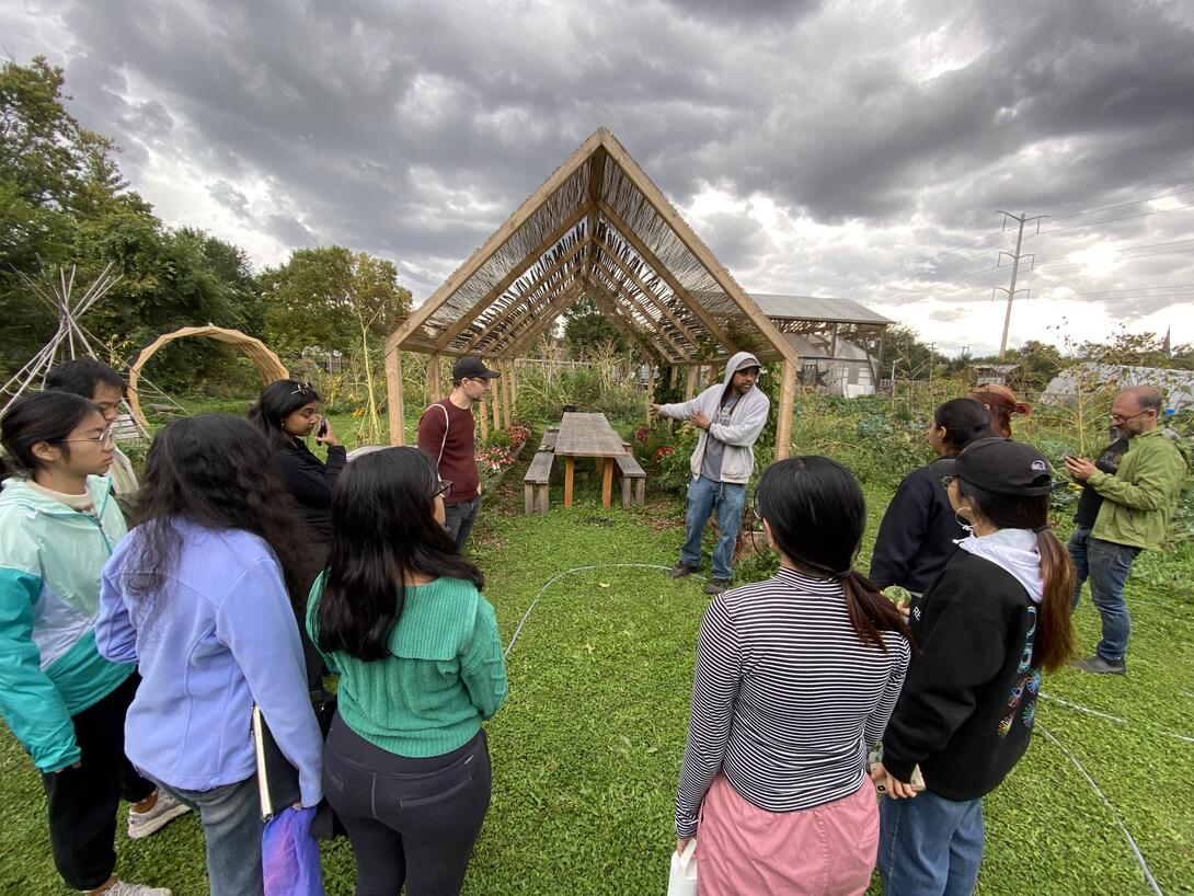 a group standing in a garden with a wooden house-shaped structure