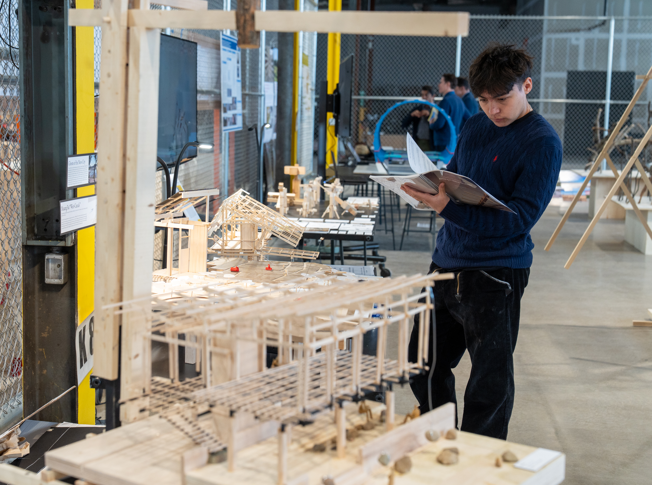 a student admires a book as part of an architectural model display.