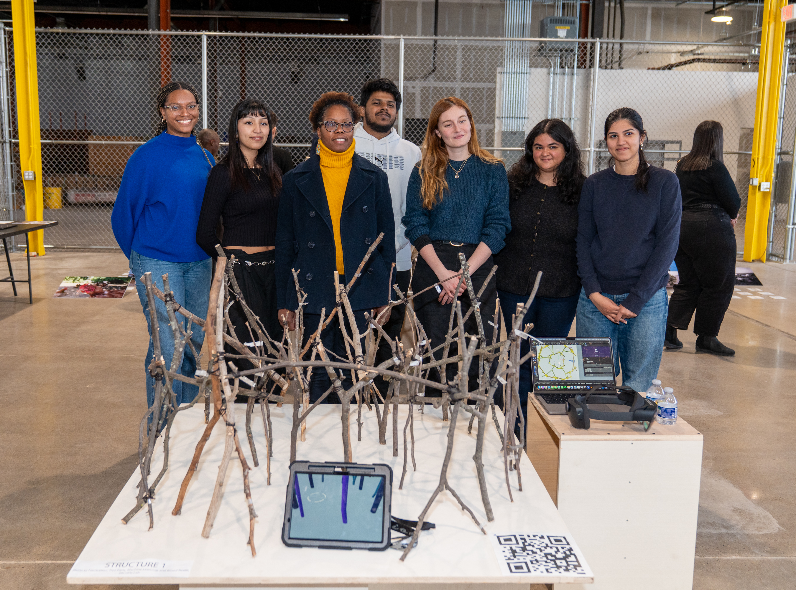 A project team poses for a group photo behind the model they created as part of their project.