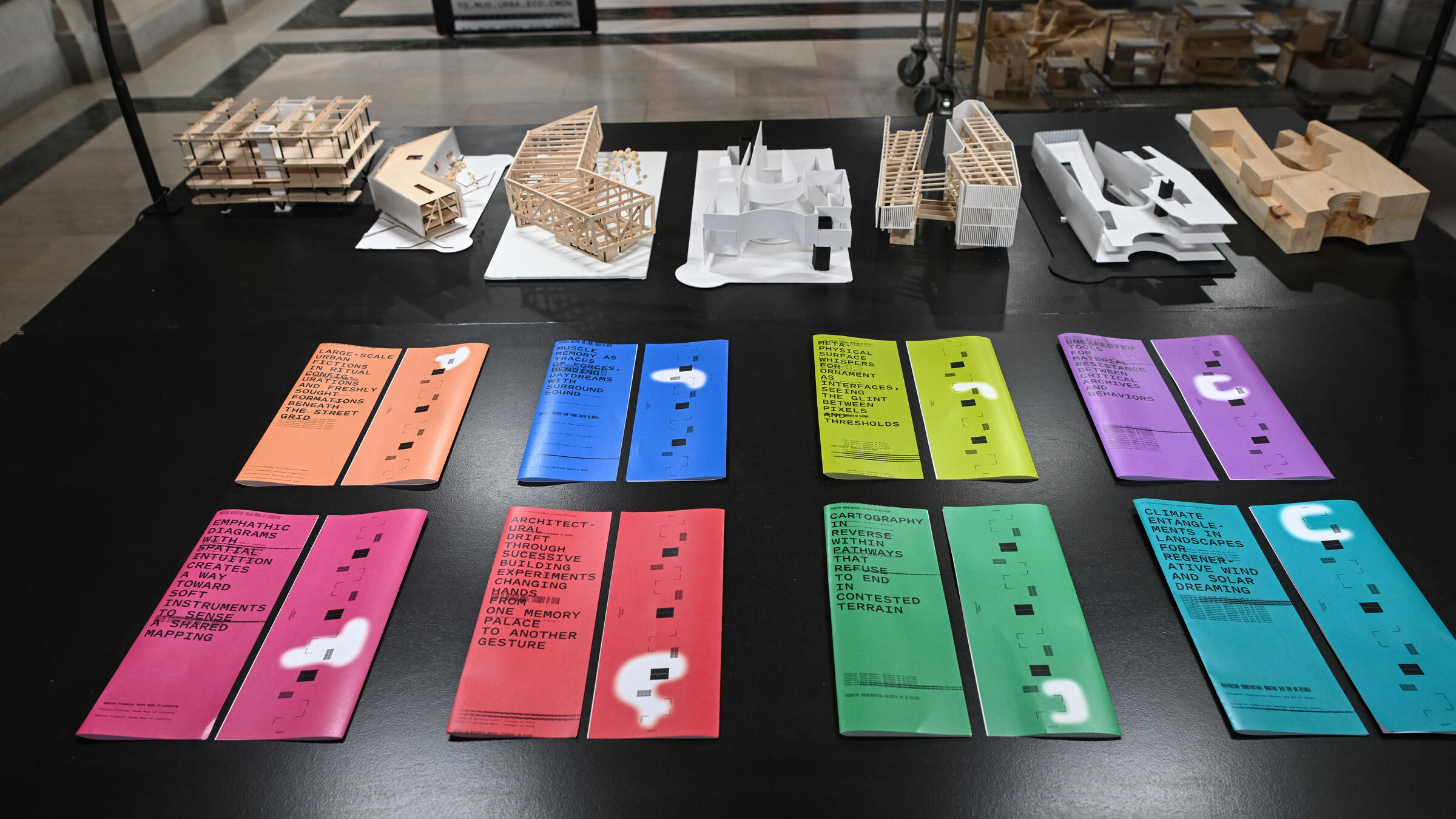 a collection of eight colorful brochures on a table in front of some architectural models