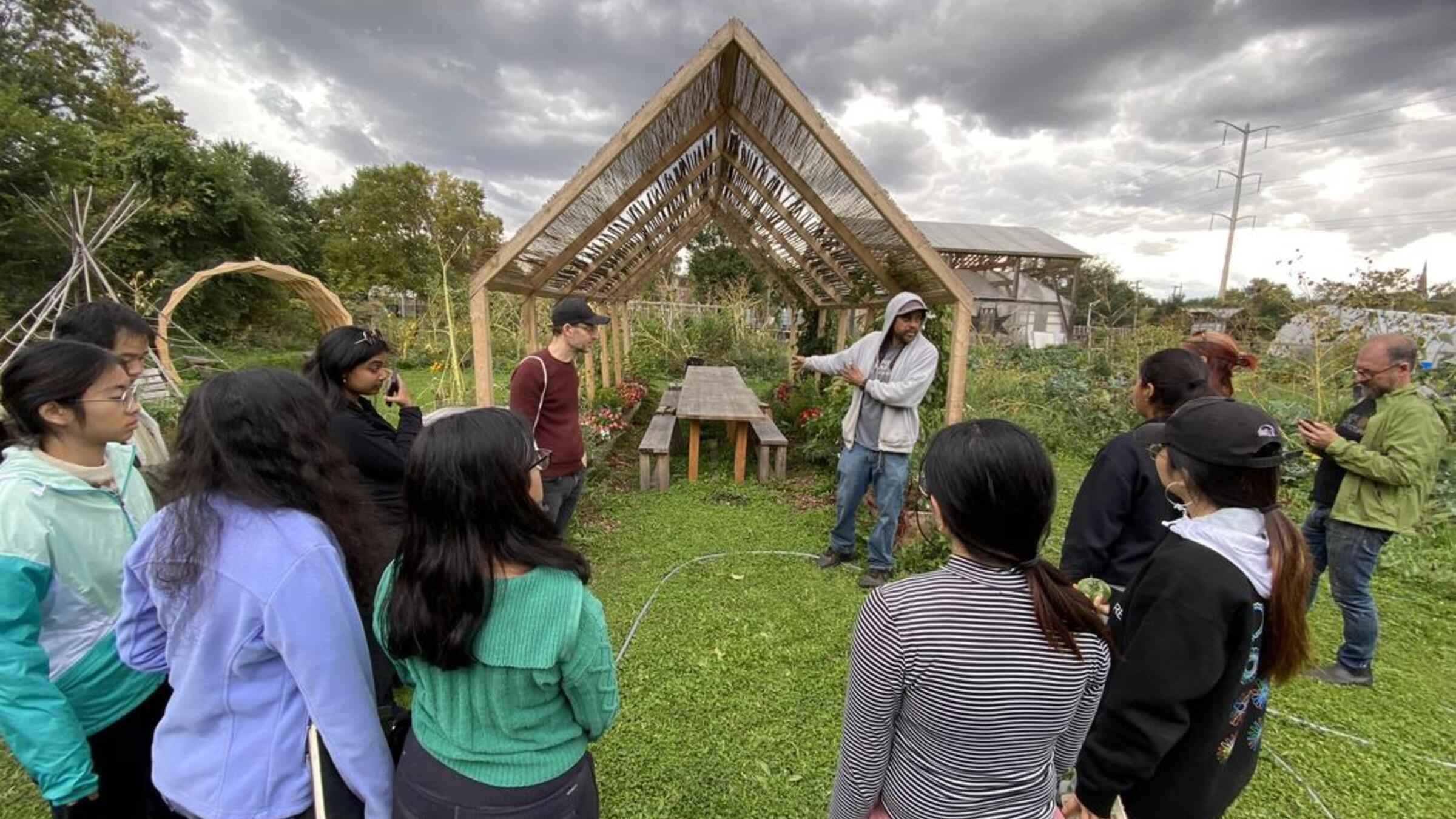 a group standing in a garden with a wooden house-shaped structure