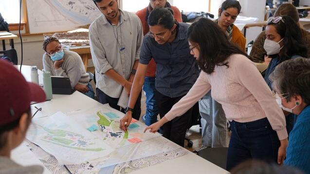 Photograph of individuals around a table looking at plans