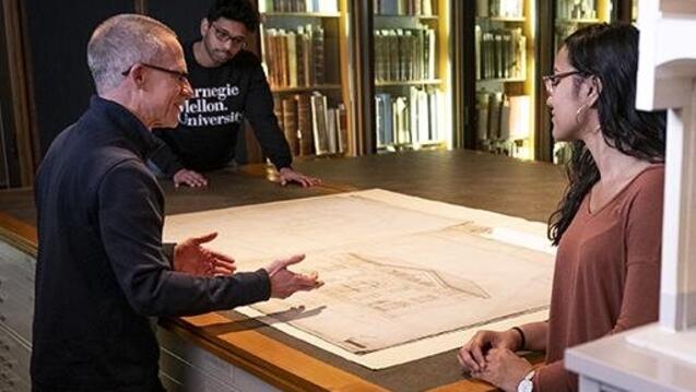 Students and library staff discuss an archival print in the library.