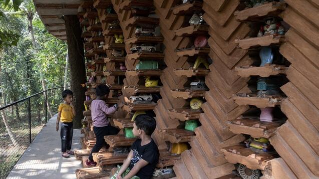 Child sitting in front of a wall made of bricks and toys