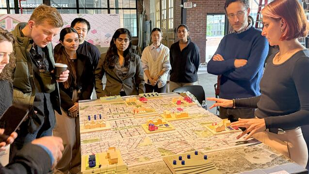 MUD students and faculty gather around a thesis project