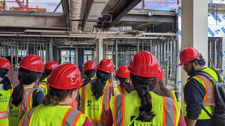 Photograph of group at a construction site wearing hard hats and visibility vests