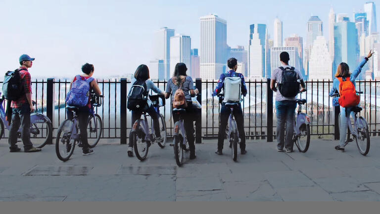 A group of adults on bicycles admires the Pittsburgh skyline