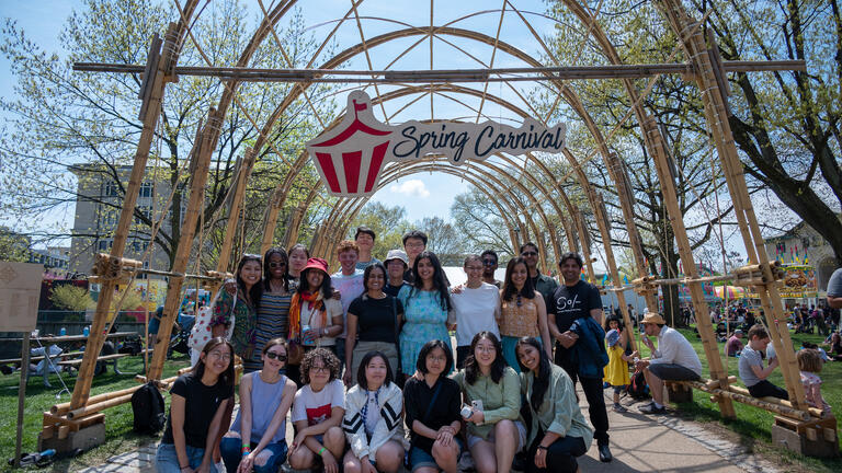 people stand in front of a bamboo structure