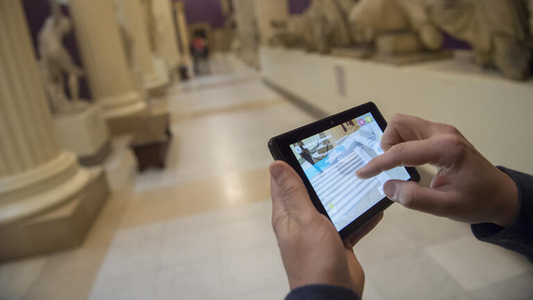 two hands holding a tablet displaying an augmented reality program