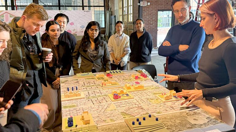 MUD students and faculty gather around a thesis project