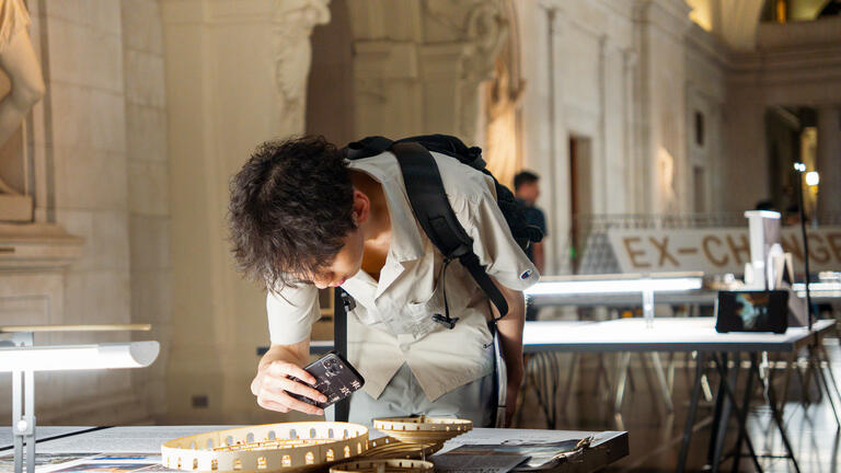 student admiring architectural model on display in the CFA great hall
