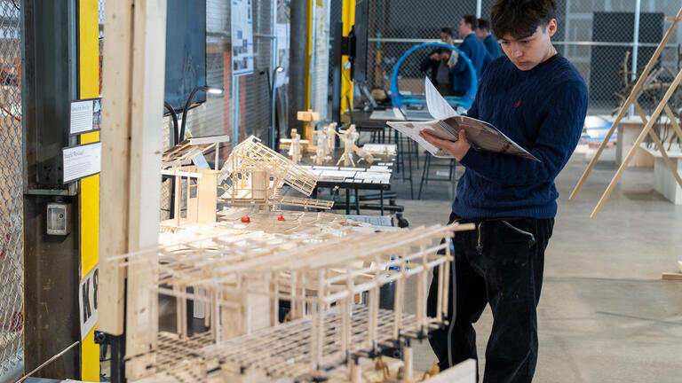 a student admires a book as part of an architectural model display.