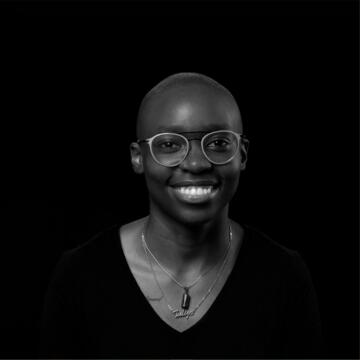 black and white photo of person with glasses wearing two necklaces