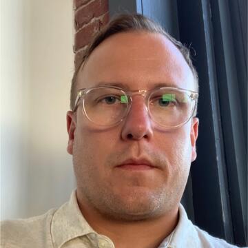 person with short hair and clear glasses
