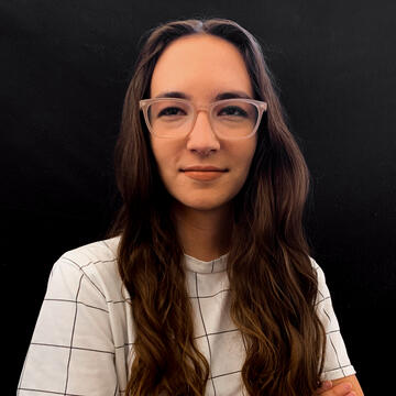 person with long hair and glasses wearing a white shirt on a black background