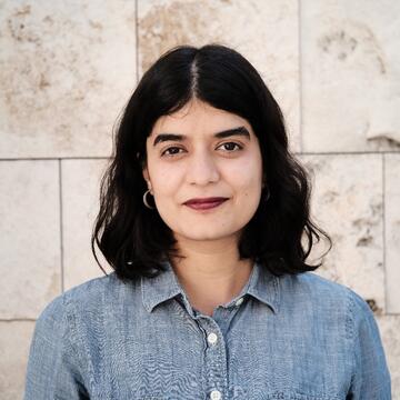 person with short dark hair wearing a chambray button-down shirt
