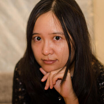 person with dark hair resting their head on their hand