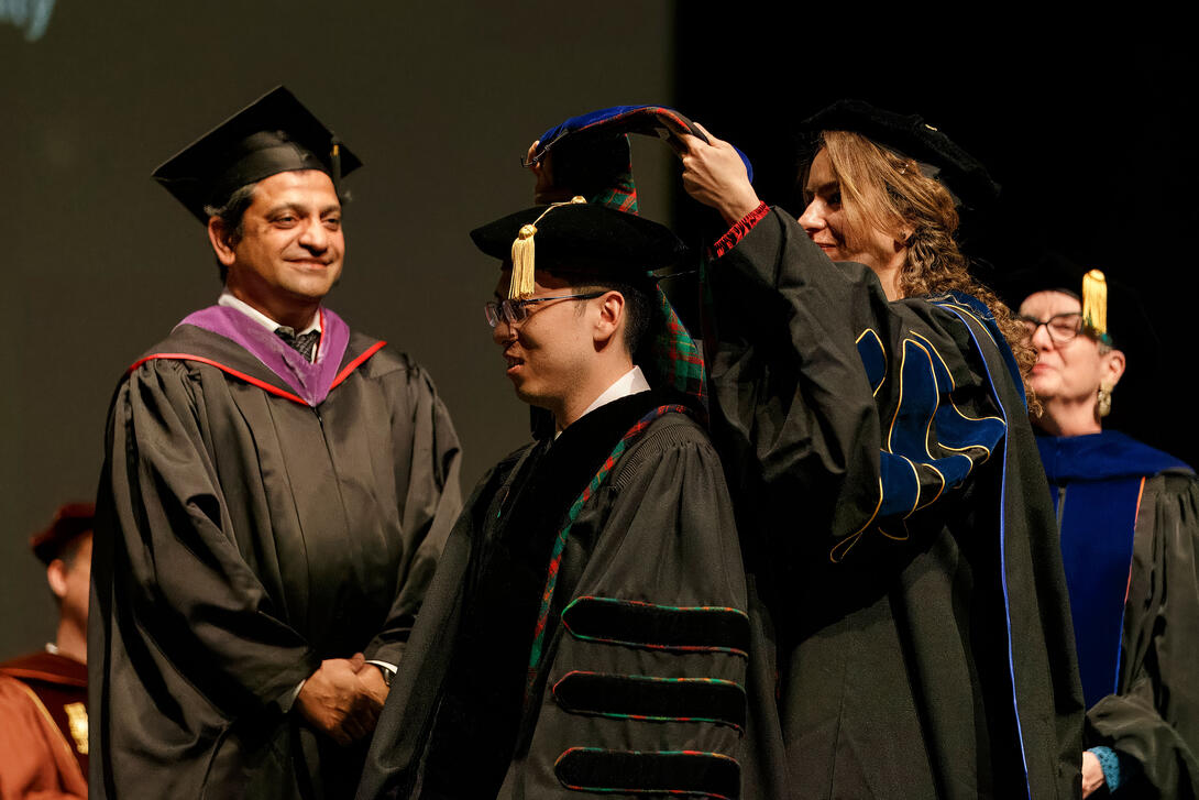A PhD graduate is hooded by a faculty member during the doctoral hooding ceremony as part of the Architecture diploma ceremony. Credit: Long Q Hong a faculty member participates in a PhD hooding during the Architecture graduation ceremony Credit: Long Q Hong