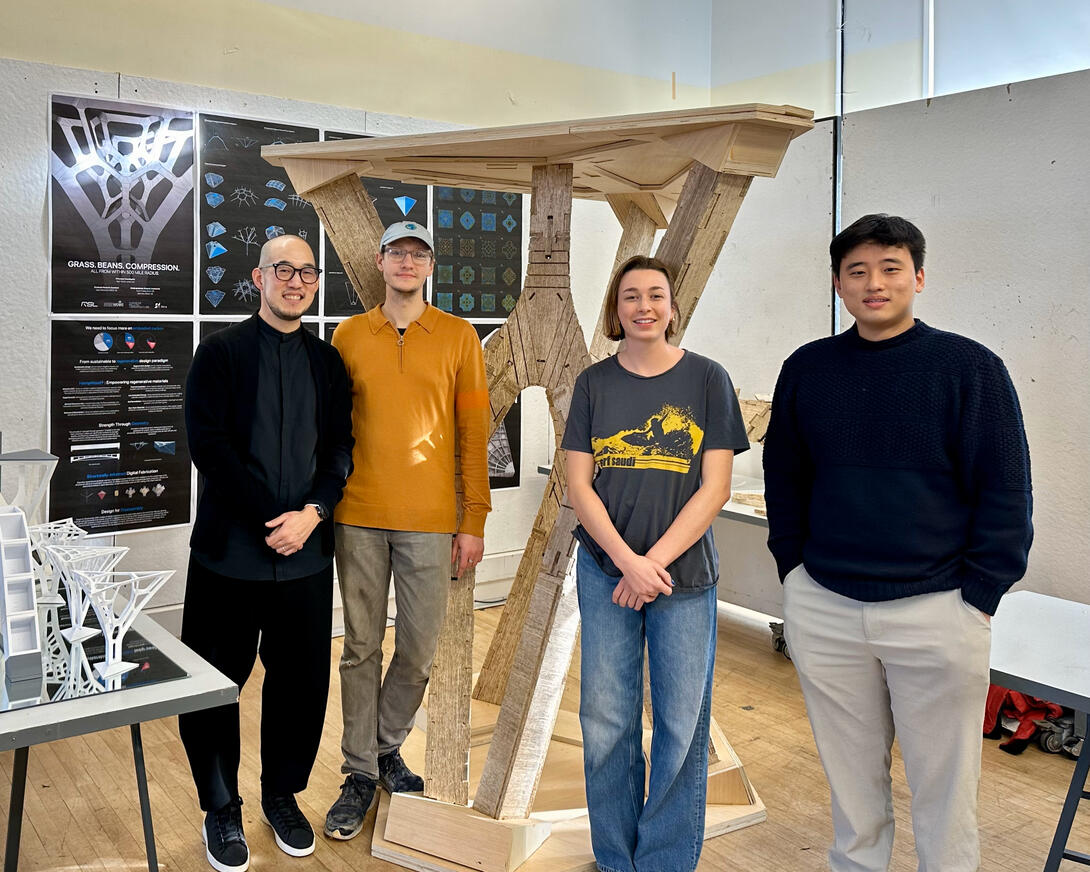 four researchers pose in front of a model