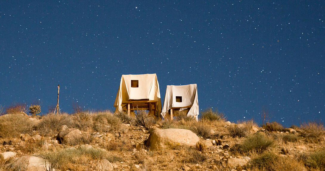 two structures in a desert with the night sky in the background